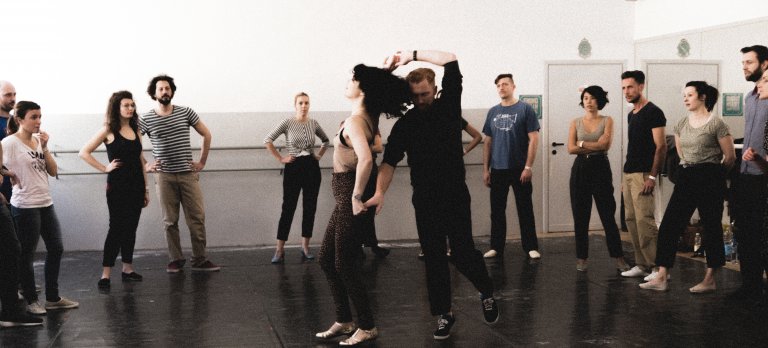 A group of people surrounding two swing dancers