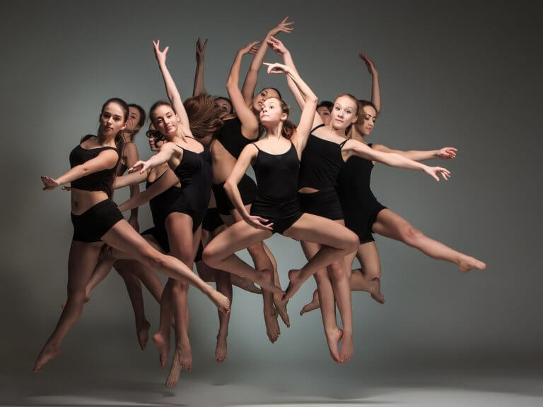 Jazz dancers jumping in front of a grey backdrop